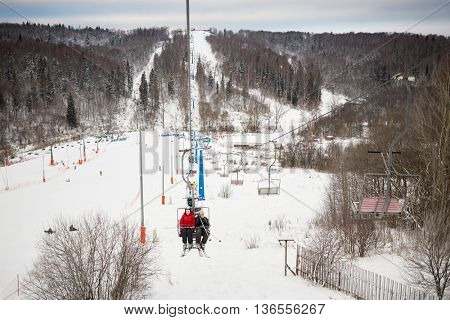 People rise on cableway on winter day at ski resort.