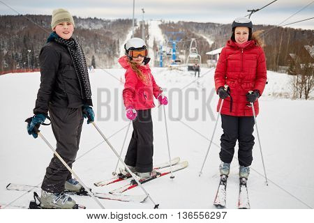 Woman and two children ski in winter at ski resort.