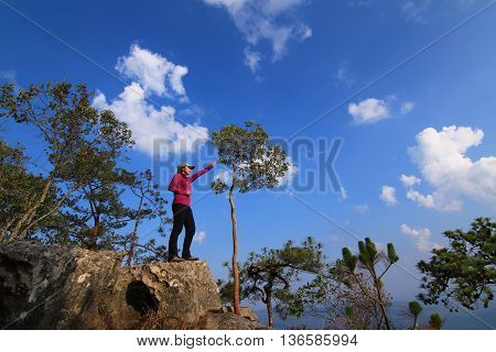 Hiker with backpack enjoying valley view from top of a mountain