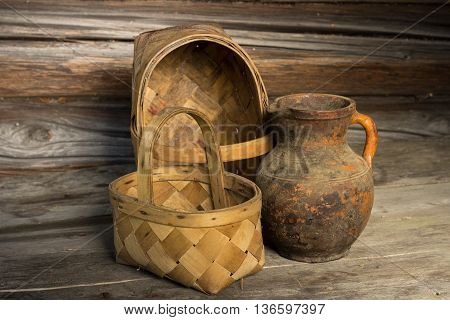 two ancient baskets and old clay jug on the wooden background