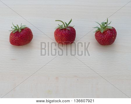Three stasty strawberries lying on the cutting board