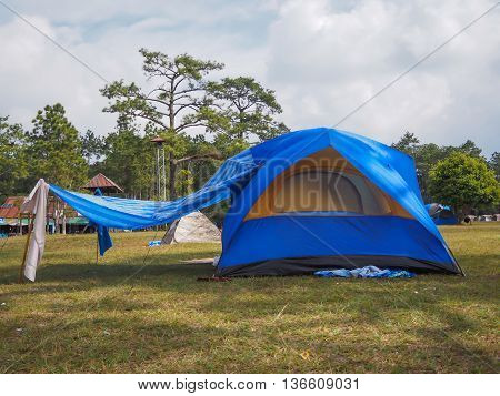 blue camping tent on the grass with cloudy sky