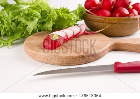 red radishes and resh green lettuce on wooden cutting board