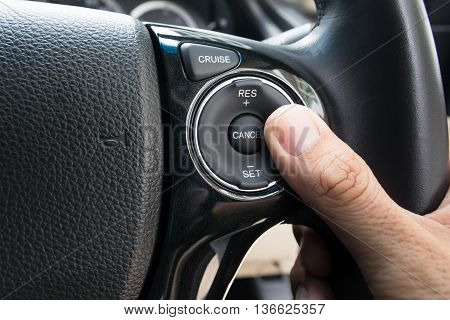 hand pushes Cruise control buttons on modern car and speed limitation