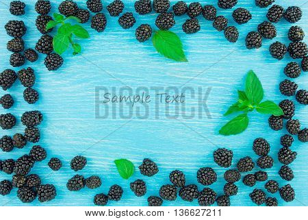 Blackberies on a blue wooden background. Free space for text.