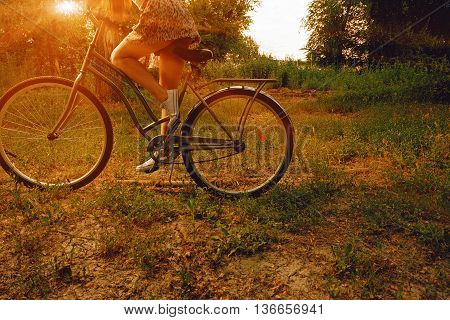 Vintage image of young hipster girl on city bike fixie at the park. Summertime. Freedom teenager with her happy vacation travel.
