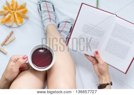 Woman Reading A Book And Having Cup Of Tea