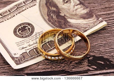 Two wedding rings and money. Dollars. Golden rings
