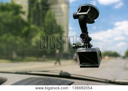 Action camera with suction cap on car windshield window filming the driving experience in urban traffic environment