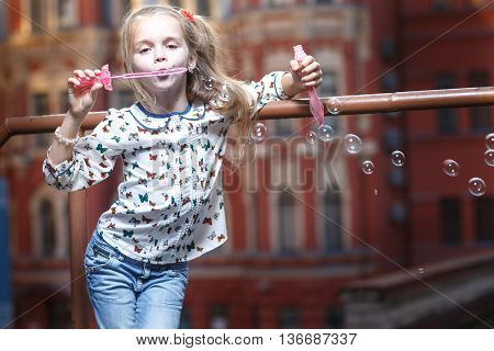 Little girl blowing bubbles on urban background