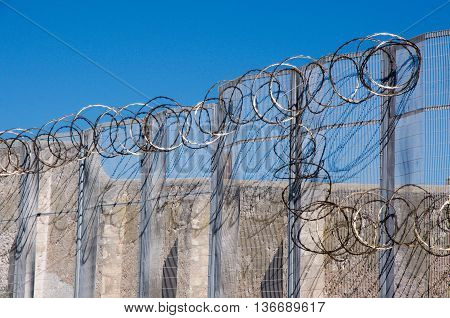 FREMANTLE,WA,AUSTRALIA-JUNE 1,2016:  Fremantle Prison detail of the sharp razor wire fencing with the limestone walls in Fremantle, Western Australia.