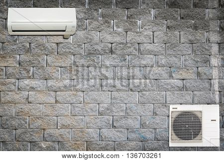 Wall air conditioning and compressor hanging on a brick wall.