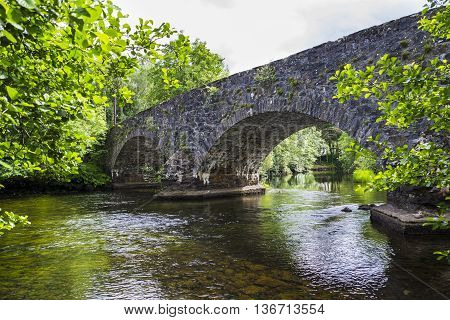 The arches of the stone hump back bridge over the River Balvag at Balquhidder Scotland.