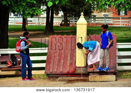 Old Salem North Carolina - April 21 2016: Three students check out an old-fashioned wooden water pump on Main Street -