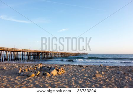 Surf waves near historic wooden pier in city of San Buena Ventura Southern California