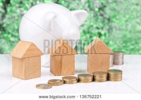 Wooden block houses and coin stacks in a row with a green background