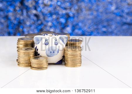 Piggy bank with a stack of coins and a blue blurry background