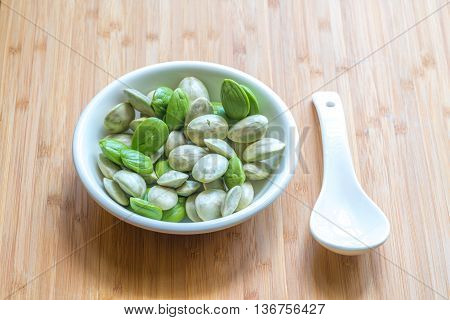 Parkia speciosa ( petai bitter bean twisted cluster bean stinker or stink bean) with white cup and spoon