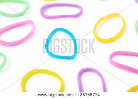Surface covered with multiple colorful resin loom bands over the white background, shallow depth of field composition