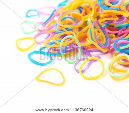 Pile of multiple colorful rubber toy loom bands isolated over the white background, close-up crop fragment foreshortening
