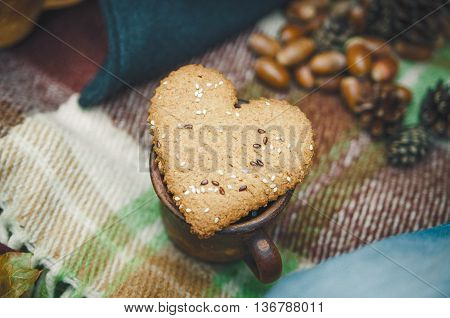 Two Heart Form Cookie is on the Wool Plaid with Autumnal Leaves and Acorn.Selective Focus.Toned