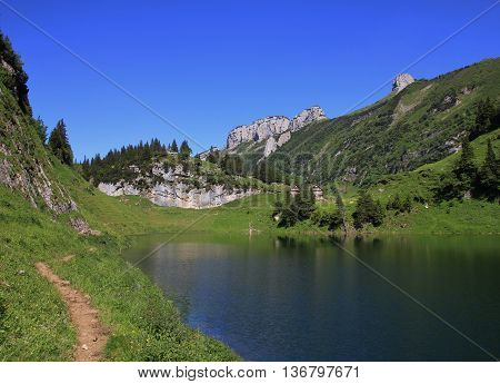Summer scene in the Swiss Alps. Hiking trail and lake Fahlensee. Bollenwees.