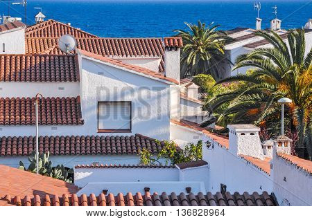 Housetops from terracotta tiles palm trees blue sea. Travel destination. Costa Dorada Spain. Horizontal.