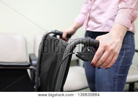 woman holding handles of wheelchair in lobby of hospital ready to transport patient