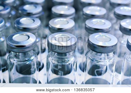 Glass vials for liquid samples. Laboratory equipment for dispensing fluid samples. Shallow depth of field.