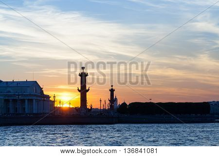 Rostral column and arrow of Vasilyevsky Island under the bright sunset sky.