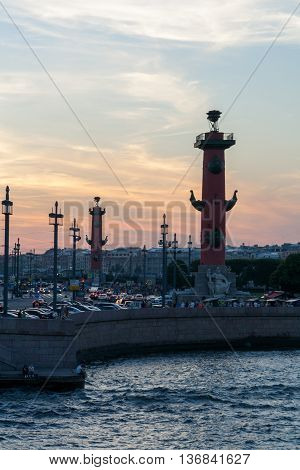 Rostral column and arrow of Vasilyevsky Island under the bright sunset sky.