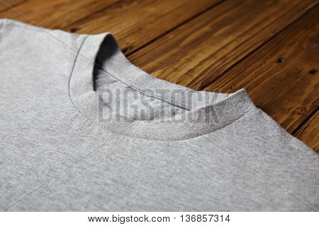 Blank grey t-shirt isolated on wooden rustic table close view on neck part mockup