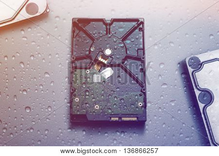 Hard disk drive covered with water drops symbolizing water damage.