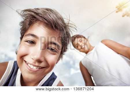 Portrait of a happy boys smiling to camera and having fun, over grey sky background, allow oneself to enjoy the pleasure of freedom in a summer camp