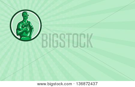 Business card showing illustration of a green plastic toy construction worker standing wearing hard hat holding nailgun and other hand on hips set inside circle on isolated background done in retro style.