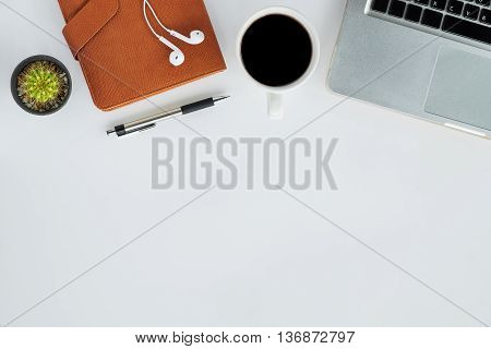 Top view of white office desk table with laptop leather notebook pen headphone and cup of coffee.Office gadgets with copy space