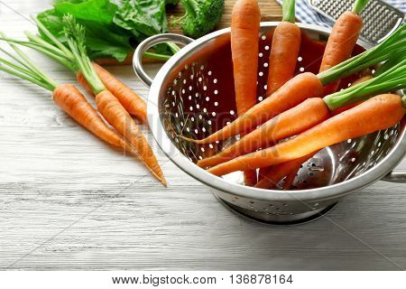 Carrots in colander on wooden table