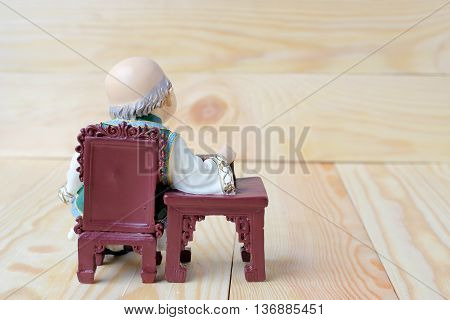 Happy Grandfather In Chinese Doll Is Listening Music On  Wood Background