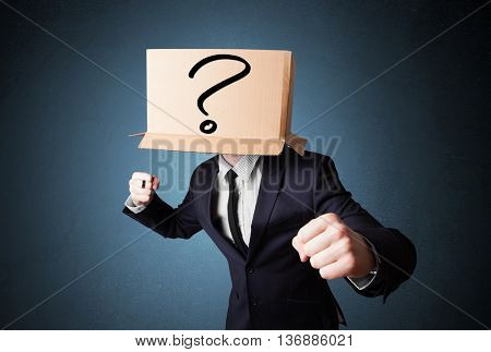 Businessman standing and gesturing with a cardboard box on his head with question mark