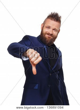 Man gesturing thumb down sign isolated at white. Young stylish hipster with beard in blue suit showing negative emotion. Sarcastic male portrait symbolising loss and failure, disapproving something.