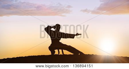 Fighter performing karate stance against clouds