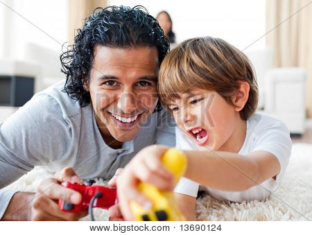 Ragazzino eccitato e suo padre video-giochi sdraiato sul pavimento in salotto