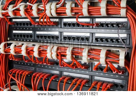 Rows of red network cables connected to router and switch hub in server room at internet data center