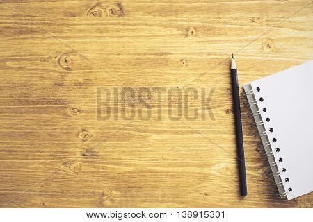Top view of wooden desktop with blank spiral notepad and pencil. Mock up