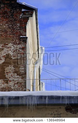 Roof with drain. Peeling winter wall with icicles