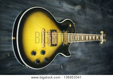 Closeup of black and yellow electric guitar on wooden surface