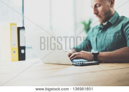 Bearded hipster working wood table laptop Modern Interior Design Loft Office.Man Work Coworking Studio, Use contemporary Notebook, typing keyboard.Blurred Background.Creative Business Startup Idea