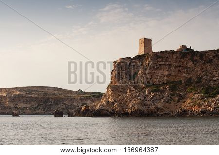 Ancient stone tower on cliffs in Malta as sun is setting.