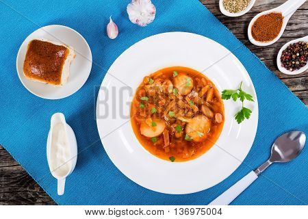 East European cuisine. Ukrainian vegetable and meat soup borscht in a white wide rim dish view from above