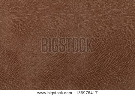 Matte brown fabric imitating animal fur. Leather background. Textured cloth.